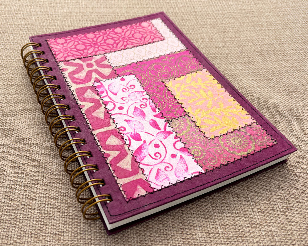 Spiral notebook with pink patchwork cover made from layers of handmade paper