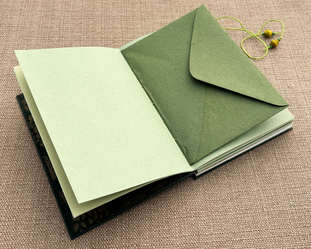 envelope stitched into binding of green journal