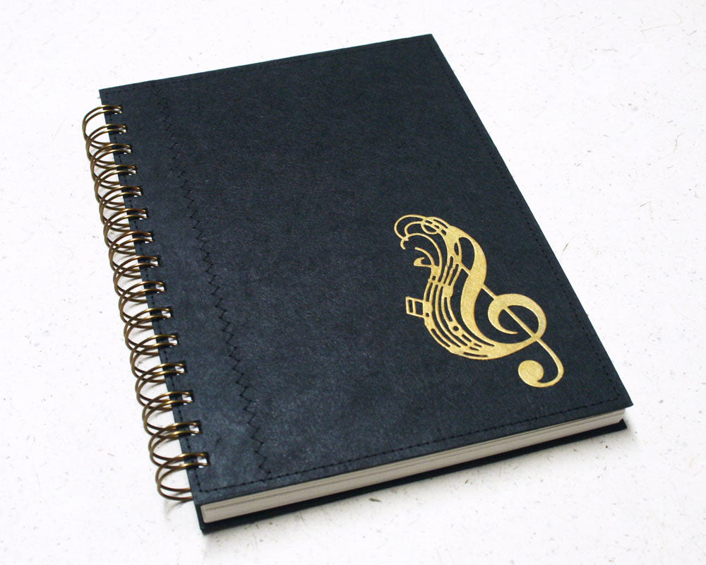 handmade music notebook with black cover featuring a gold treble clef in the corner